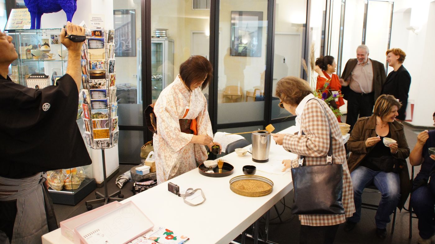Besucherinnen probieren an einem Tisch im Stadtmuseum japanisches Kunsthandwerk aus